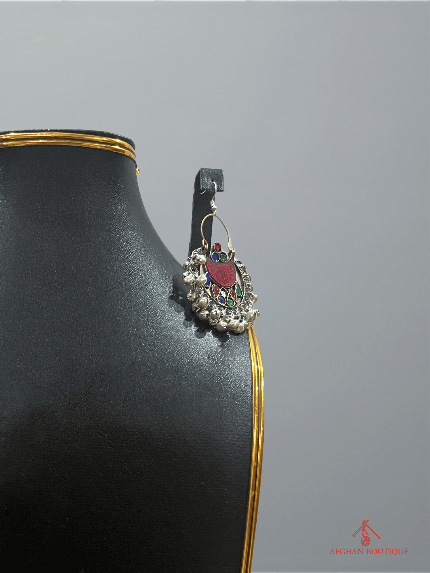 Close-up of left multicolor handcrafted Afghan earring with detailed tribal patterns and gemstone accents.
